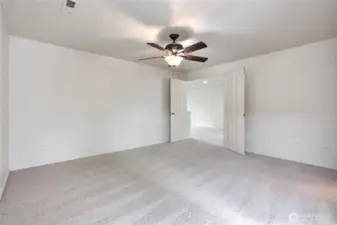 Primary bedroom suite has double doors and ceiling fan.