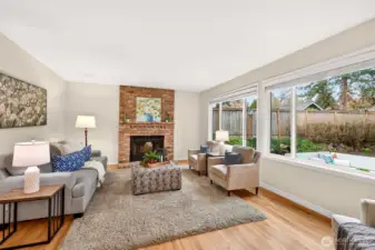 The adjacent family room is warm and comfortable, anchored by a classic brick fireplace and large backyard facing windows that bring in soft natural light. It is a true everyday living space, well suited for relaxing, gathering, and spending time together.