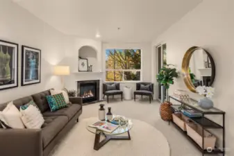 Spacious living room with gas fireplace, slider to private balcony, and oversized window with green outlook.