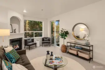 Spacious living room with gas fireplace, slider to private balcony, and oversized window with green outlook.