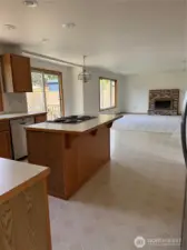 Kitchen open to family room with cozy fireplace.