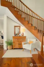 Welcoming entry with seating area and curved staircase to second level.