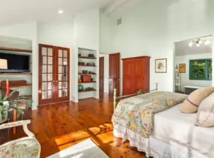 Large primary with double doors to Juliet balcony and built in shelving for books and entertainment center.