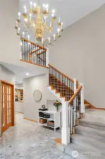 Dramatic foyer with marble floor, vaulted ceilings, and grand staircase