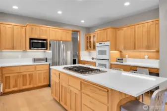 Open concept kitchen with white quartz counters, oversized island, eating area, and LVP flooring