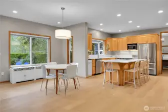 Open concept kitchen with white quartz counters, oversized island, eating area, and LVP flooring