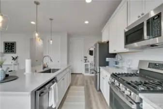 Perfect kitchen for entertaining, large island & beautiful quartz counters, 5 burner gas stove, & counter-depth stainless steel refrigerator.