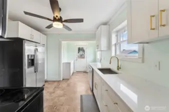 Brand new kitchen cabinetry, quartz countertops, and sink! Door to the backyard at the end of the kitchen