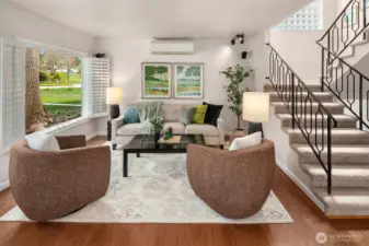 The living room is light and spacious with surround sound built in and a huge picture window looking out to green views.