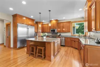 A large open kitchen with slab granite, gorgeous stainless appliances, Oak hardwood flooring and clear Hemlock cabinetry.
