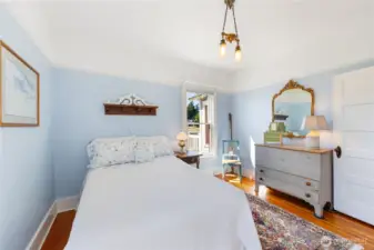 Main level bedroom with a large closet behind and built in dresser drawers.  Wood flooring brings warmth to this inviting bedroom space with natural sunlight.