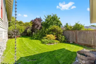 Lush, green side yard with professional landscaping and irrigation.  That shadow is the roof of the Garage with a door to access from here.