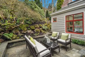 Bluestone patio just off the kitchen with built-in bench seating & lovely landscaping beyond.