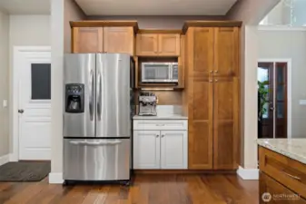 There is a coffee bar between the refrigerator and the pantry. The door to the left of the fridge opens to the 3-vehicle garage.