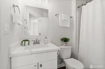 Bright and inviting bathroom featuring quartz counters, contemporary lighting, and a full-size tub
