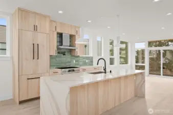 Boasting an elongated floating island, this bright kitchen features breakfast bar seating, flush refrigerator, and tasteful green backsplash.