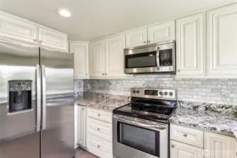 Granite counter tops w/stainless steel appliances in kitchen
