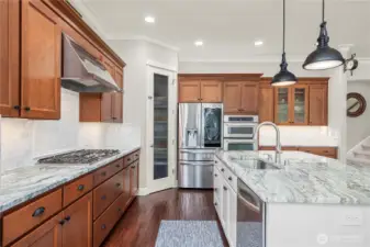 Bright kitchen layout featuring gas cooktop, microwave, oven, large refrigerator, walk-in pantry, and generous storage.