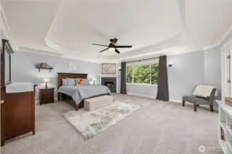 Expansive primary suite with tray ceiling, fireplace, and large picture window overlooking the private backyard, creating a serene retreat.