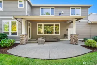 Spacious covered patio with stone-accented columns and private backyard views, perfect for year-round entertaining.