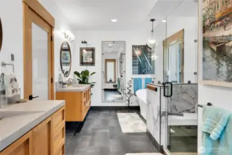The bathroom features a tile-and-glass shower, a soaking tub, custom floating white oak cabinets with concrete vanity tops and integrated sinks, durable materials with functional design.