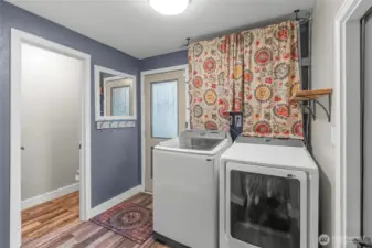MAIN FLOOR | This bright space is the laundry room with a half-bath to the left and a door to the garage to the right. The door straight ahead leads to the back yard.