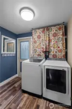 LAUNDRY ROOM | Perfectly located, the door leads to the backyard. Not pictured is a half-bathroom to the left. The tankless water heater is hidden behind the curtains above the washer and dryer.