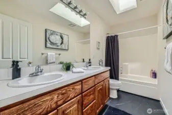 Half bath with a dual sink vanity and tub/shower combo.
