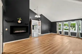 Main floor primary suite — bright, spacious, and full of character with French doors, vaulted ceilings, bay windows, and an inviting electric fireplace.