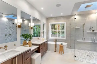 Elegant and serene, the primary bathroom showcases luxurious finishes and thoughtful design. Soft natural light filters through the skylight, highlighting the sleek quartz surfaces, designer fixtures, and custom cabinetry. Every element—from the freestanding tub to the expansive glass-enclosed shower—blends spa-level comfort with modern sophistication.