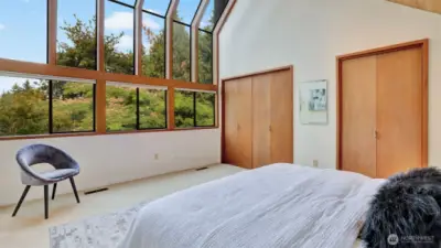 Wake up to stunning treetop views in this light-filled bedroom with soaring windows.