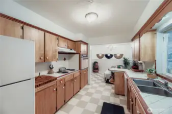 Functional galley kitchen with abundant cabinet space, large window over the sink, and direct access to the dining area.