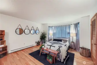 Spacious primary bedroom with hardwood floors, bay window seating area, and abundant natural light.