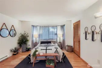 Generously sized primary bedroom featuring hardwood floors, a bay window seating area, and abundant natural light.