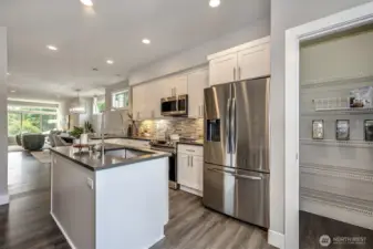 Wide plank luxury laminate flooring throughout main floor, full height tile back splash, slab quartz counters, island, stainless appliances and walk-in pantry make this the ideal chef's kitchen.