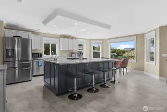 Spacious, open concept kitchen and dining look out to living room with fireplace