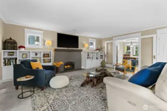 Living room off kitchen with built-ins, a cozy gas fireplace and new flooring