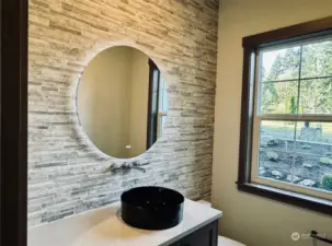 Powder room features stone wall & backlit mirror