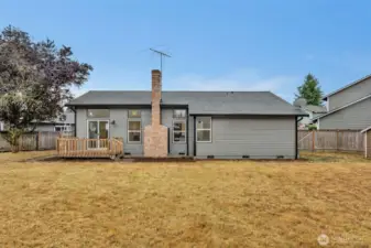 The home's rear elevation showcases the deck for outdoor dining and the generous yard space beyond.