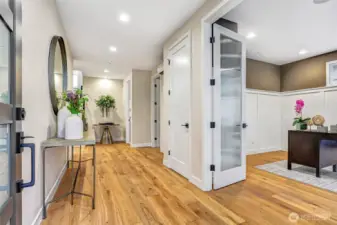 Inviting entry hallway with wide-plank hardwoods and designer lighting. French doors open to a private main-level office with custom millwork and oversized windows that bring in natural light.