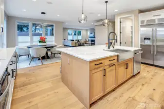 The oversized center island is the true hub of the home, offering generous prep space, seating, and seamless connection to the dining and great room. Warm wood tones, sleek black hardware, and modern globe pendants add layered texture and sophistication, while the open layout keeps the kitchen at the heart of daily living and entertaining.