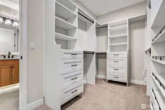 Spacious walk-in closet with custom built-ins, generous hanging space, and soft carpet underfoot — an organized dressing retreat right off the primary suite