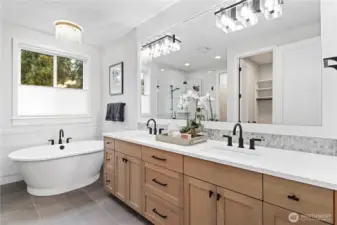 The serene primary bath offers a spacious slab-quartz double vanity with a millwork-framed mirror. Refined freestanding tub with chandelier and wainscot wall tiling.