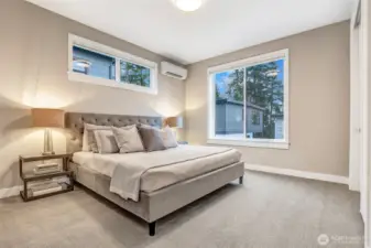 Spacious secondary bedroom with large windows, soft neutral palette, and ample room for full-size furniture.