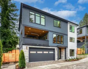 Crisp daytime view of the home’s contemporary façade with stone accents, wide driveway, and welcoming covered entry.