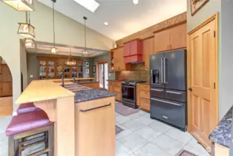 View of kitchen with custom copper sink, gas stove and tile flooring.