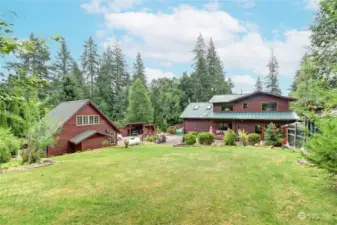 Back yard view to the house and the detached garage on the left.  Outbuilding storage is between the two off the driveway.