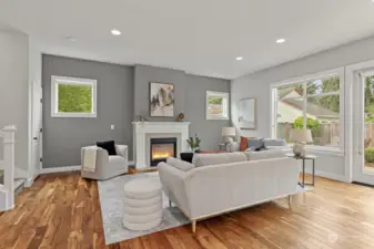 The living room is bright and spacious, outfitted with engineered hardwood floors, large windows and a cozy fireplace.