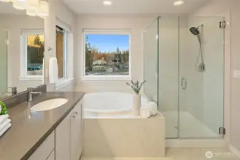 Ensuite bathroom features a soaking tub and walk-in frameless tile shower