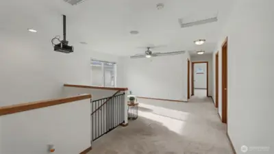 A spacious upstairs loft designed for family, fun, or work, featuring a projector and screen that stay for effortless movie nights.